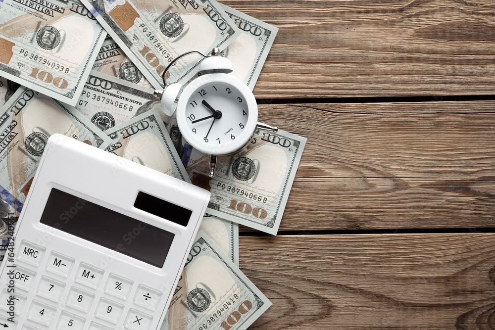 Many dollar bills with alarm clock and calculator on a wooden table. Business concept. Time is money Many dollar bills with alarm clock and calculator on a wooden table. Business concept. Time is money