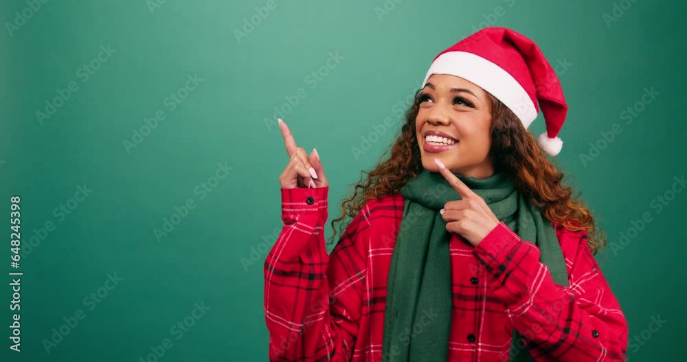 Beautiful young woman pointing left to copy space, Christmas Santa hat studio