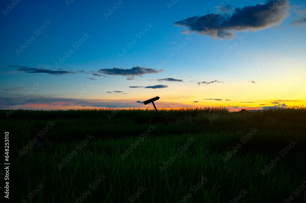 silhouette cross sign on graveyard grass land in evening sunset sky