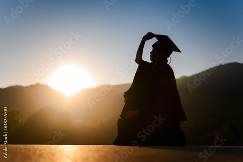 Silhouette of university graduate woman in landscape mountains sunset background photo