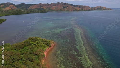 Drone footage of Coastline and recife in  in Coron in Philippines. We do a simple dolly movement to catch the beautifulness of the recife and beach nearby. There is mountains in the landscape behind photo