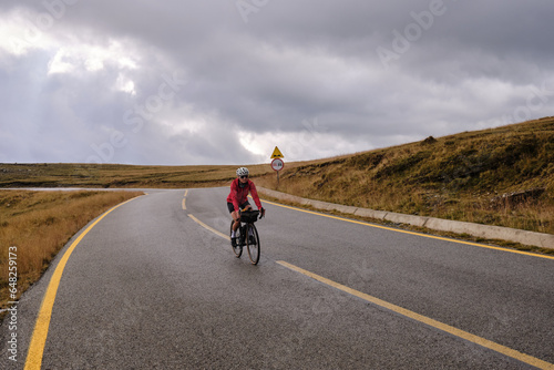 Female cyclist in bike packing tour.Bikepacking travel.Female cyclist is riding through foggy mountain landscape.Adventure cycling concept. Woman cycling in the nature.Transalpina road.Parâng Mountain