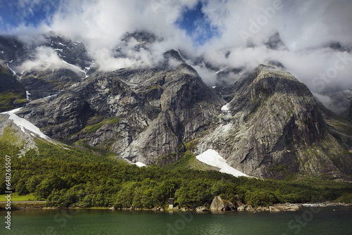 Traces Of Snow On Mountains Along The Water's Edge With Clouds Covering The Peaks; Andalsnes, Rauma, Norway photo