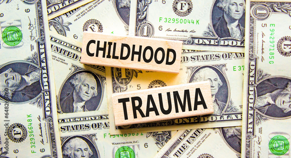 Childhood trauma symbol. Concept words Childhood trauma on beautiful wooden blocks. Dollar bills. Beautiful background from dollar bills. Business psychology childhood trauma concept. Copy space.