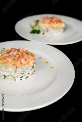 Beautiful serving dish salad under the crooks and garnished with herbs on a 2 two white plate food restaurant on a black background