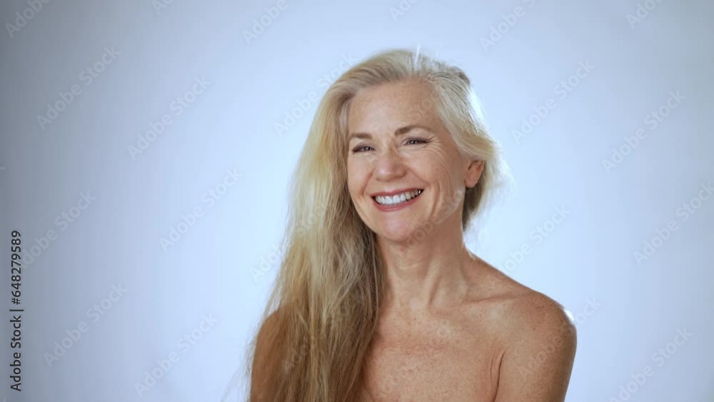 Portrait of smiling playful flirting happy 50s, 60s middle aged woman with blond gray hair flipping it around. Old healthy skin care spa beauty concept, skincare treatment, cosmetics. Slow motion Portrait of smiling playful flirting happy 50s, 60s middle aged woman with blond gray hair flipping it around. Old healthy skin care spa beauty concept, skincare treatment, cosmetics. Slow motion