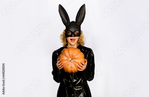 Happy Halloween. Sexy girl in bunny mask with halloween pumpkin. Preparation Halloween holiday. Sensual woman in rabbit ears licking lips with tongue. Halloween party. Bunny woman with Jack-o-lantern.
