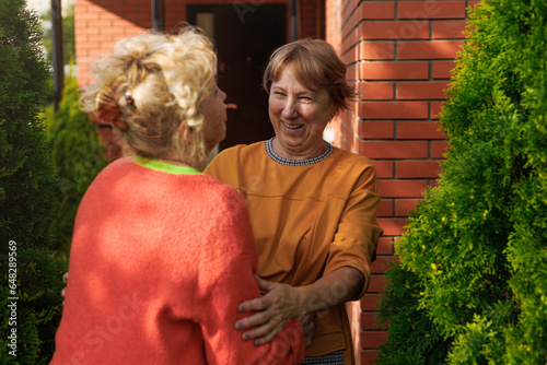 Senior friends, greeting and hug outdoor by house, funny and laughing together. Elderly women, handshake and embrace, happy and smile for bonding, care and welcome to retirement reunion in backyard