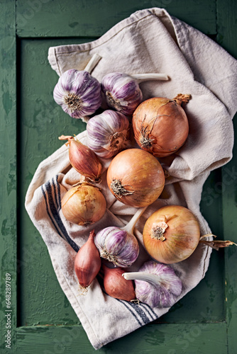 Purple garlic bulbs and onions on a linen towel. Top view. Natural, healthy food ingredients
