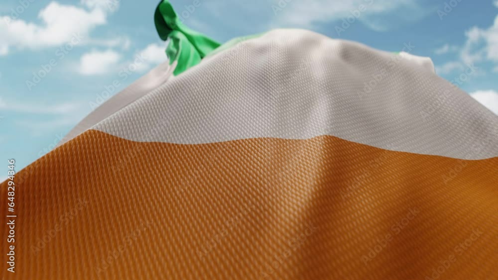 Wavy flag of Ivory Coast blowing in the wind in slow motion. Waving colorful Ivorian flag team symbol abstract vertical background. Blue sky with clouds. World countries flying flags concept