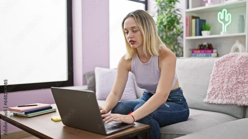 Young blonde woman using laptop sitting on sofa smiling at home Young blonde woman using laptop sitting on sofa smiling at home