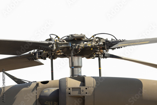 Close-up detail of helicopter blades and rotor mechanism in front of white sky.