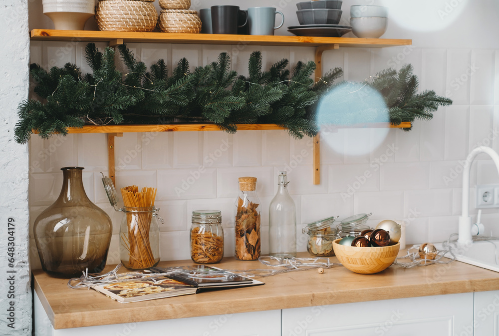 Christmas decor on the kitchen with garland. Festive home interior. Christmas tabletop setting over Defocused lights, bokeh. Eco style, pastel color Christmas decor on the kitchen with garland. Festive home interior. Christmas tabletop setting over Defocused lights, bokeh. Eco style, pastel color