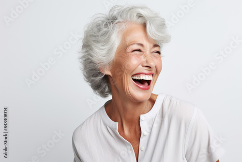 A closeup photo portrait of a beautiful elderly senior model woman with grey hair laughing and smiling with clean teeth. used for a dental ad. isolated on white background.