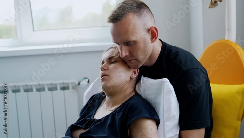 Exhausted Caucasian woman lies in her husband's arms. Pregnant lady is tired from painful contractions. photo