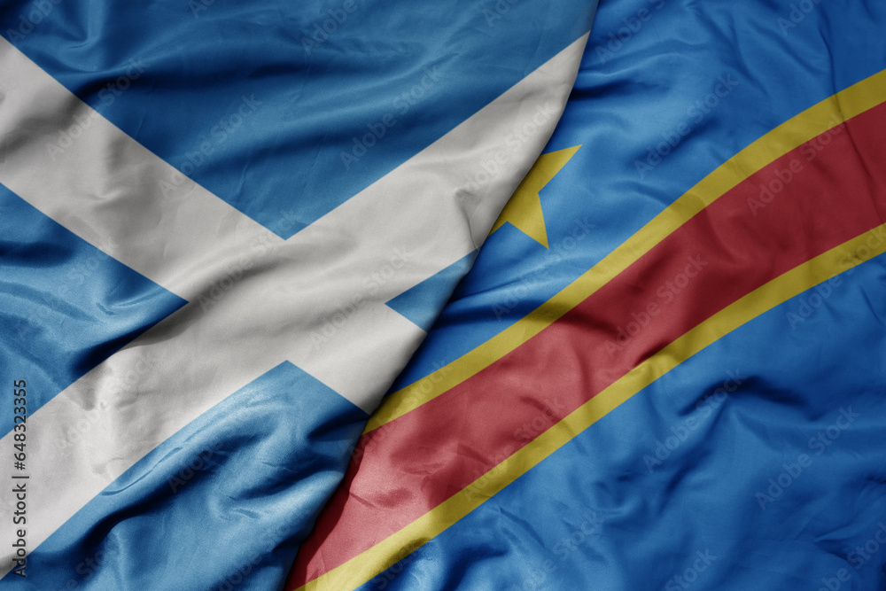 big waving national colorful flag of scotland and national flag of democratic republic of the congo .