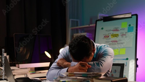 Asian man in dark office, company employee working overtime, working in the middle of the night, working overtime of a company employee who is busy and working hard. Overtime concept.