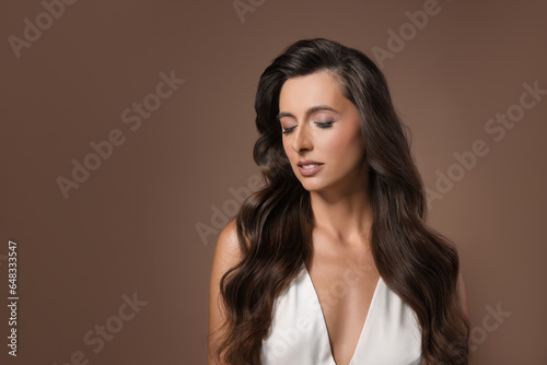 Hair styling. Beautiful woman with wavy long hair on brown background, space for text