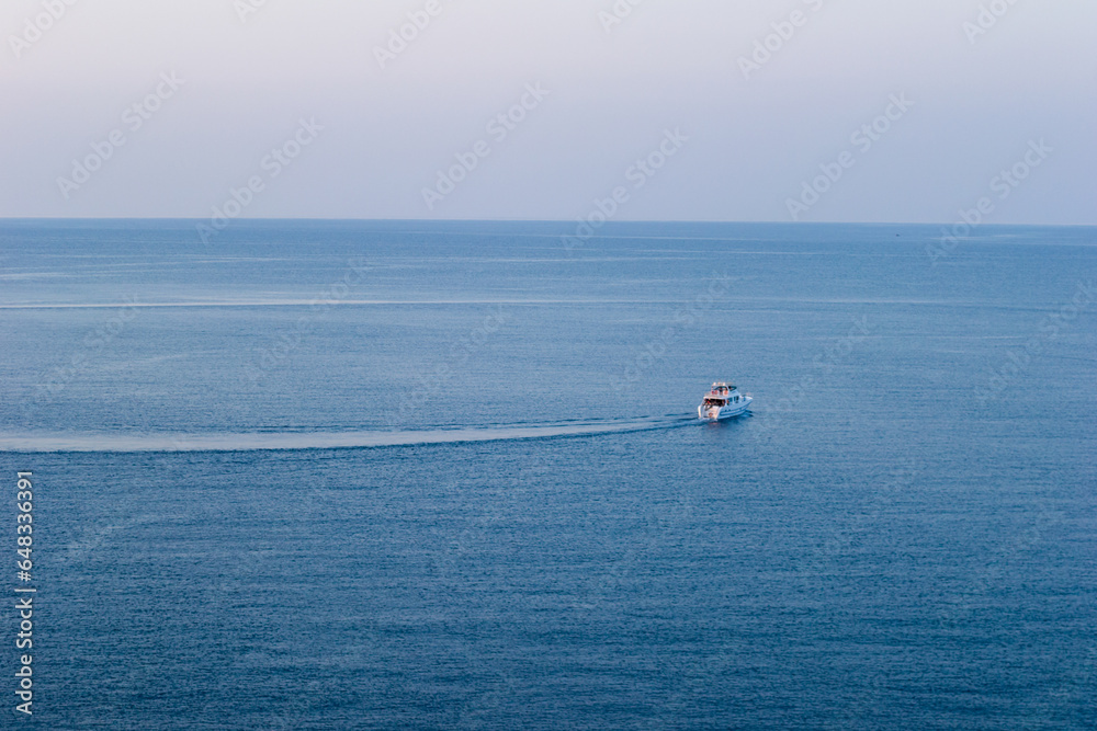 Naklejka premium Single boat in the sea in sunset light, Antalya