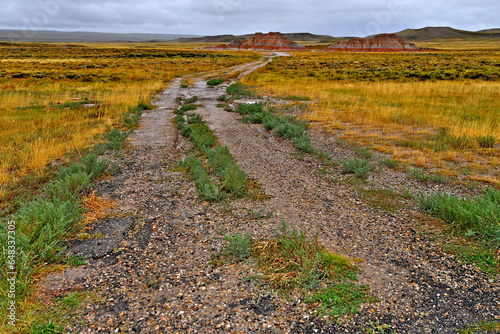Raining, Wet and Cold. “An adventure for another day”. View to old remnant paved road heading toward erosional remnants of colorful strata, Highway 189, Wyoming  photo