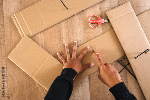 Top view of male hand cutting cardboard box with cutter photo