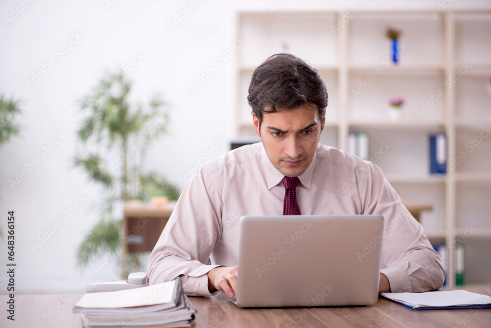 Young male employee and too much work in the office Young male employee and too much work in the office