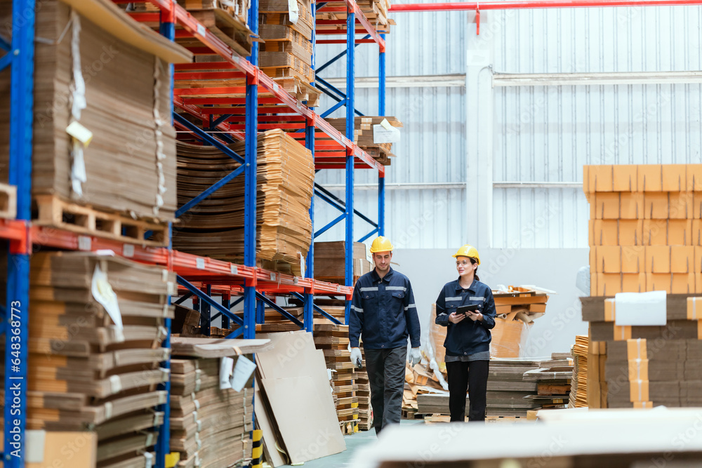 Two male and female employees are checking cardboard boxes in a warehouse for an export business.