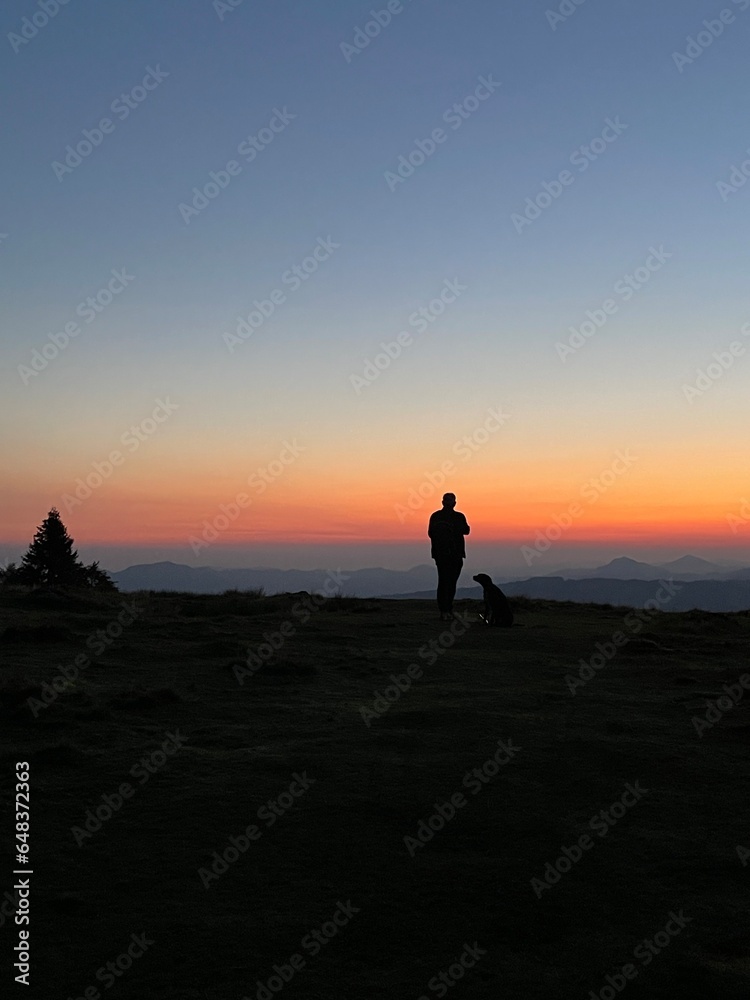 Man ans dog in sunset in the mountains