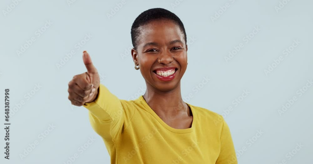 Success, smile and thank you with a black woman thumbs up in studio on a blue background for motivation. Portrait, goal and happy with a winner young person showing a like emoji to gesture yes Success, smile and thank you with a black woman thumbs up in studio on a blue background for motivation. Portrait, goal and happy with a winner young person showing a like emoji to gesture yes