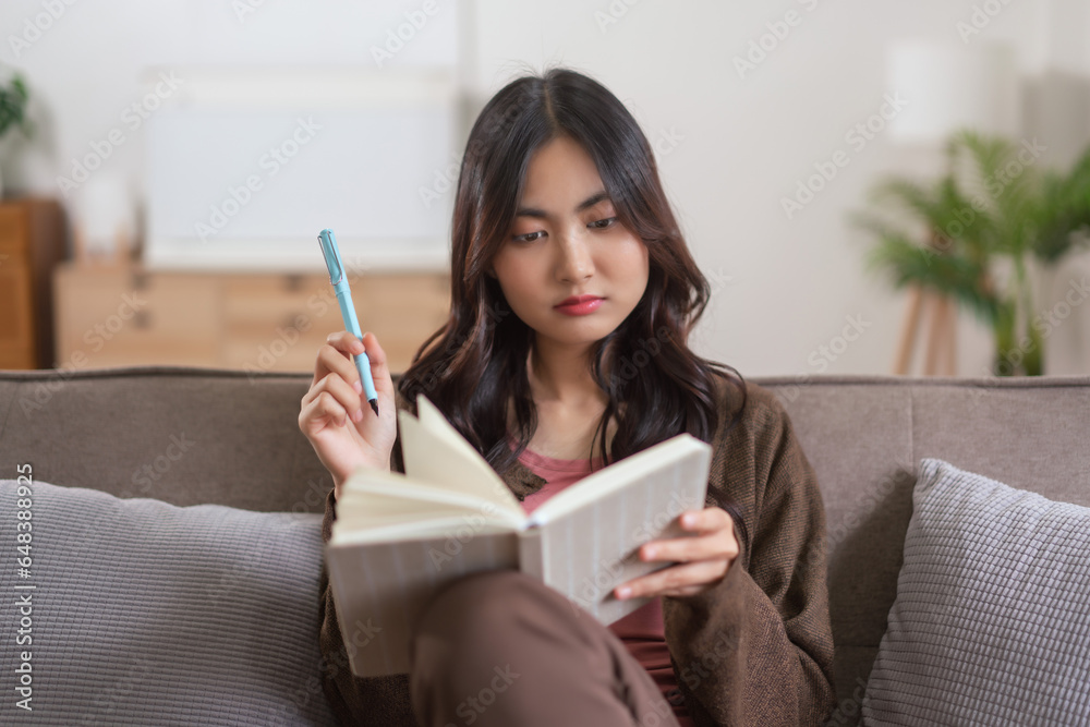 Women leisure on sofa to thinking about something and writing down on notebook in lifestyle at home Women leisure on sofa to thinking about something and writing down on notebook in lifestyle at home