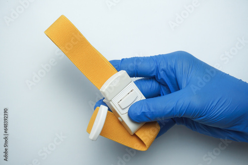 doctor wearing blue medical gloves holding a yellow tourniquet, isolated on white photo