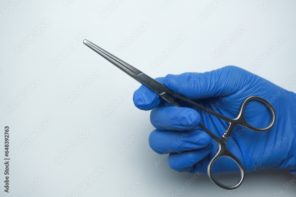 Doctor wearing blue medical gloves holding Allis Intestinal and Tissue