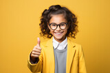 smiling schoolgirl wearing school uniform show thumb up finger on yellow background. Back to school