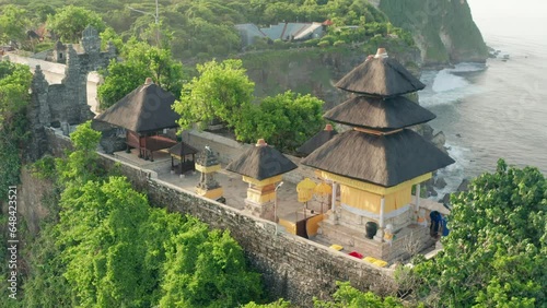 Bali's Most Iconic Landmark and popular tourist attraction Uluwatu Temple one of six key Bali temple perched on top mountain cliff on background amazing nature Bali, Indonesia. 4K Aerial view photo