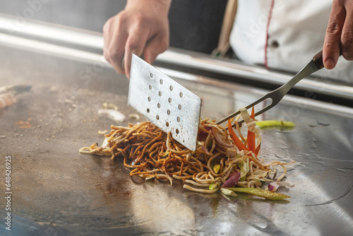 Teppanyaki chef preparing food on hot metal plate photo