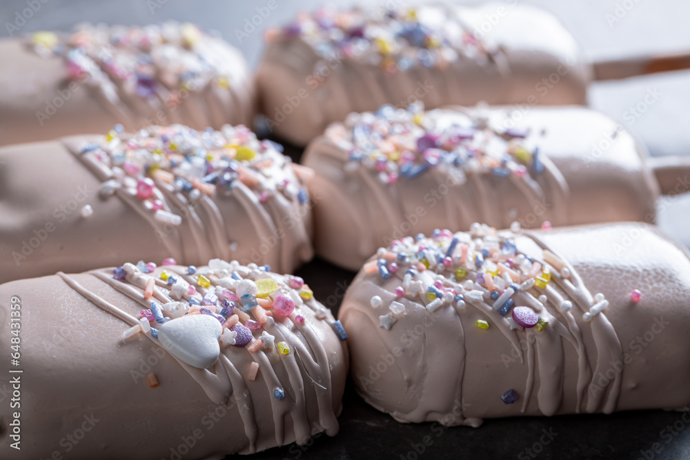 Homemade and delicious popsicles with chocolate and sprinkles topping Homemade and delicious popsicles with chocolate and sprinkles topping