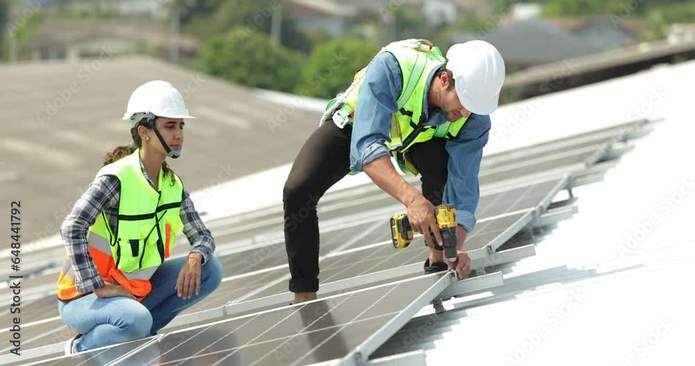 electrical engineering team man and woman worker Installing Solar Cell panels on Roof. Solar energy clean and green alternative energy. Unity and teamwork electrical engineering team man and woman worker Installing Solar Cell panels on Roof. Solar energy clean and green alternative energy. Unity and teamwork