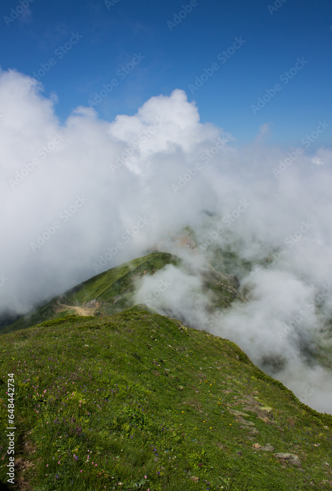 beautiful panoramic landscape - mountain peaks through white clouds against the blue sky on a sunny day and copy space