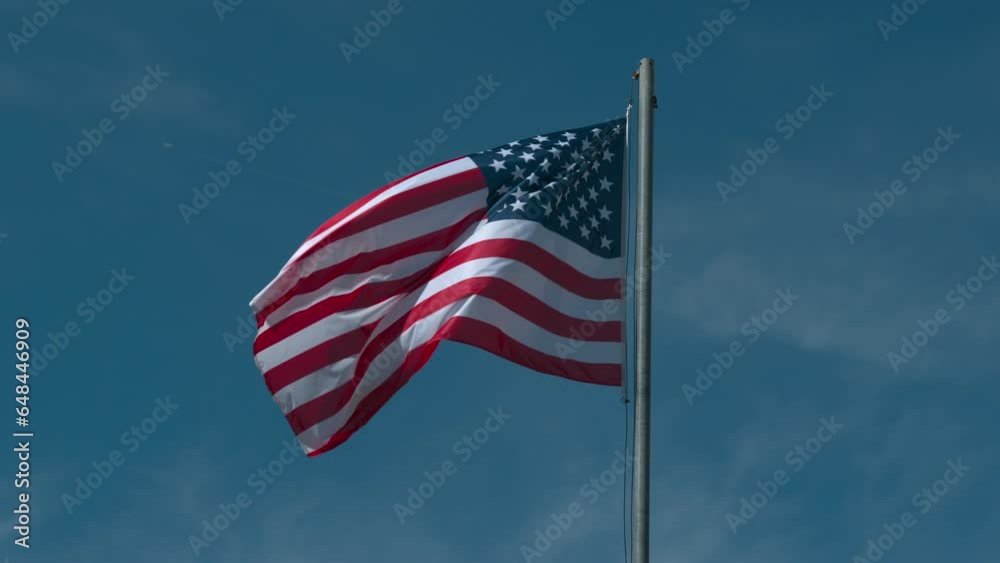USA national flag on pole waving against blue cloudless sky in slow motion. USA national flag on pole waving against blue cloudless sky in slow motion.