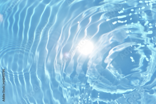 Defocus blurred transparent blue colored clear calm water surface texture with splashes reflection. Trendy abstract nature background. Water waves in sunlight with copy space. Blue watercolor shine