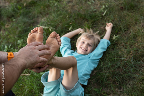 Принти на полотні man's hands tickle a child's bare feet lying on the grass