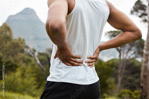 Fitness, nature and a person with back pain after running with a sports injury or accident. Tired, healthcare and an athlete or runner with muscle strain, inflammation or emergency after training photo