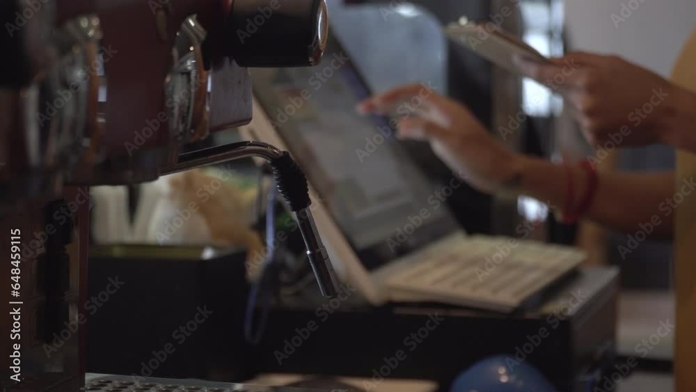 Hand of woman cashier at counter working in coffee shop cafe restaurant. Waitress in apron using finger touching screen of POS terminal in cafe shop.