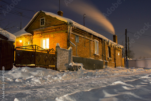 house smokes from the chimney at night in winter