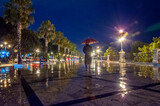 Uomo con cappotto lungo e ombrello passeggia da solo sulla via Marina di Reggio Calabria di notte