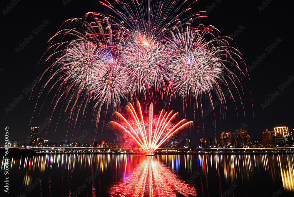 Obraz premium Colorful fireworks of various colors over night sky with reflection in water