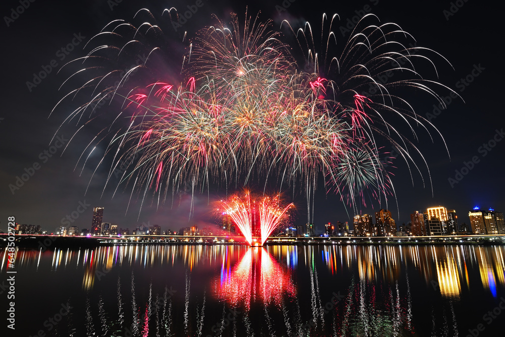 Obraz premium Colorful fireworks of various colors over night sky with reflection in water