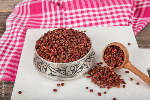 Dry spice sumac in a wooden spoon. Ground sumac spice. Dried ground red Sumac powder spices in wooden spoon with sumac berries on rustic table. Healthy food concept.