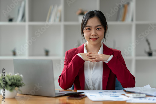 Attractive Asian businesswoman excited with laptop computer smartphone Finance, accounting, marketing, tax paperwork on office desk