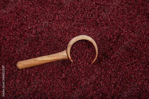 Dry spice sumac in a wooden spoon. Ground sumac spice. Dried ground red Sumac powder spices in wooden spoon with sumac berries on rustic table. Healthy food concept.